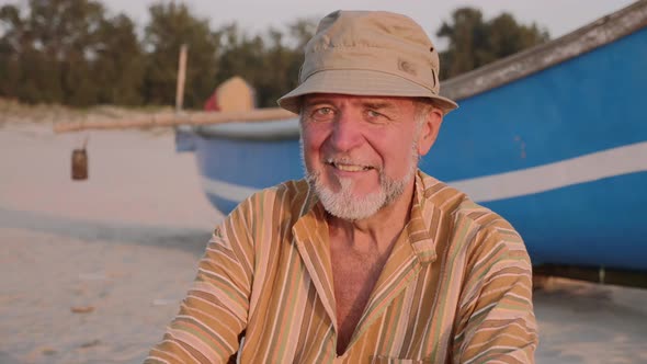 Portrait of senior fisherman in hat near his fishing boat
