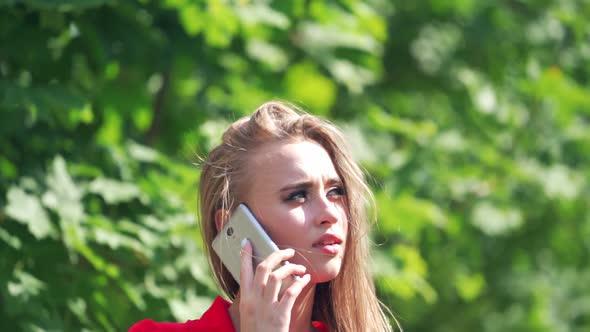 Sad woman's face outdoors. Beautiful young female talking on the mobile phone. alt