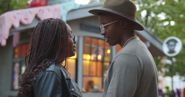 Side View of African Man and Woman Talking Outdoors Over Blurred Background alt