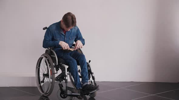 Man in Wheelchair Reading Book at Home