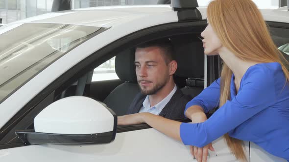 Handsome Man Talking To His Wife While Choosing New Car at Dealership Salon