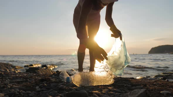 Volunteer Girl Collects Trash in the Trash Bag. Plastic Bottles and Other Trash on Sea Beach alt