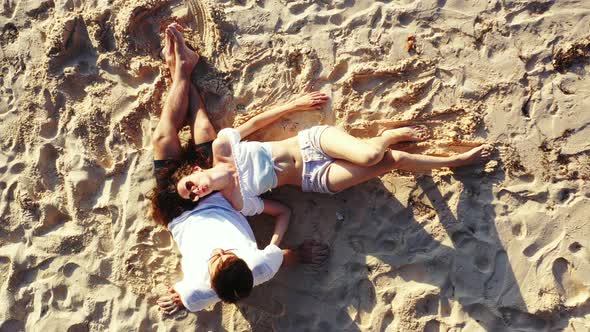 Tropical Island of the Bahamas - Couple relaxing on the sandy beach on a sunny day - Aerial Shot alt