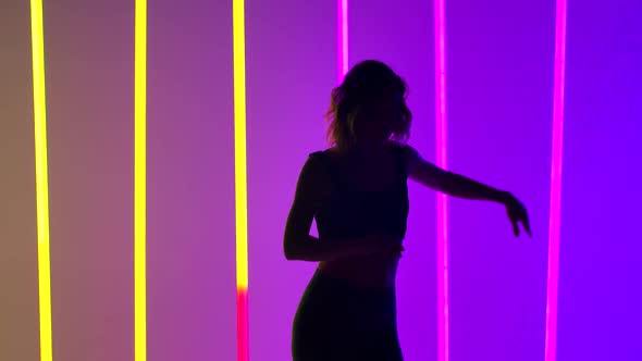 A Slender Woman in Leggings and a Top Is Practicing Salsa Movements in Slow Motion alt