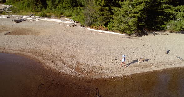 Woman with her pet dog walking near river coast on a sunny day 4k alt