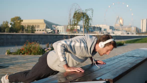 Serious Young Sportsman Doing Pushups Outside in City on Summer Day alt