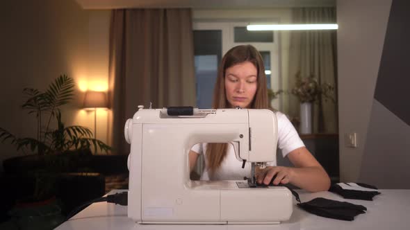  Woman Sews a Protective Mask on a Sewing Machine. Woman Works at Home.