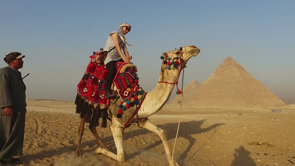 Female tourist sitting on camel in desert at Giza pyramids alt