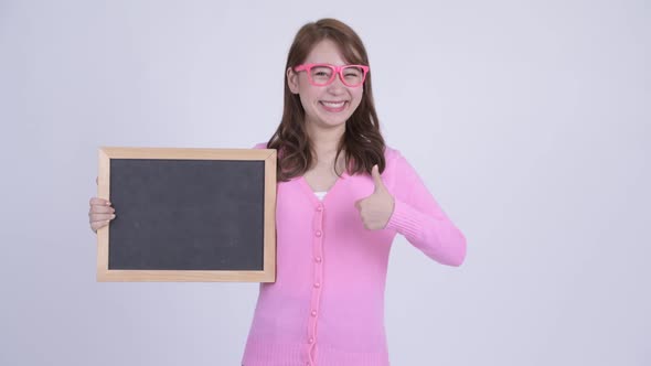 Young Happy Asian Nerd Woman Holding Blackboard and Giving Thumbs Up alt