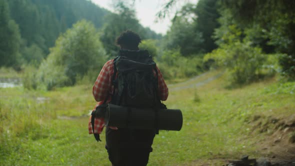 Handsome African American Man Hiker with Backpack Trekking Near Mountain River alt