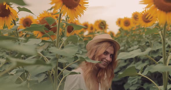 Beautiful Girl in a Hat Laughs and Has Fun in a Sunflower Field