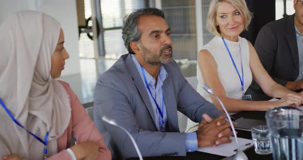 A panel of business delegates talking at a conference alt