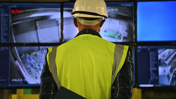 Engineer in Front of Facility Control Room Displays alt
