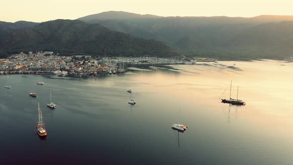 Aerial View of a Marina with Boats and Mountains in the Background alt