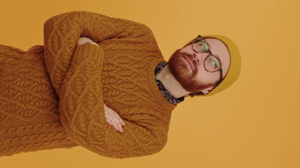 Thoughtful Bearded Hipster in His 30s Wearing the Sweater and Winter Hat Thinking Orange Background alt