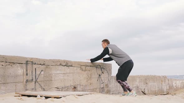 Young Man Doing Parkour Tricks on the Beach Near the Sea alt
