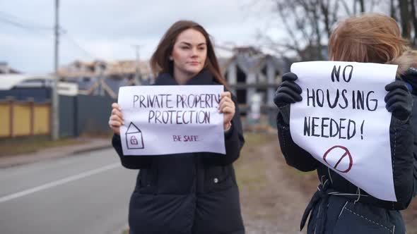 Two Caucasian Female Activists Talking Standing Outdoors with Placards alt