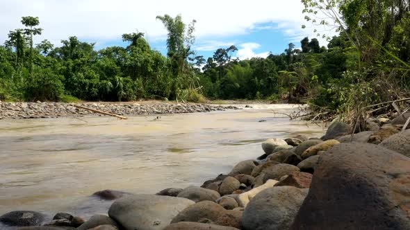 A timelapse of a tropical river with brown colored water in which the river alt