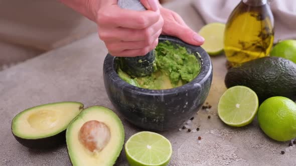 Making Guacamole Sauce  Woman Mashing Avocado in a Marble Mortar with Pestle at Domestic Kitchen alt