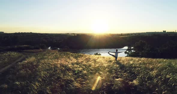 Girl doing yoga on a beautiful meadow at sunset alt