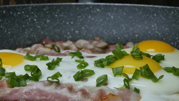Closeup Frying Bacon with Chicken Eggs and Green Onions