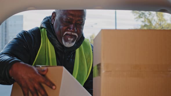 Closeup Happy Mature African American Man in Workwear Uniform Stacking Cardboard Boxes Courier alt