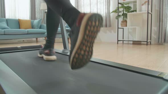 Back View Legs Of Asian Woman Running On A Treadmill At Home alt