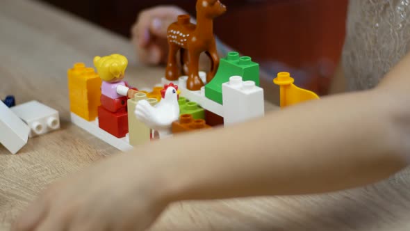 Little girl plays building blocks on a wooden table