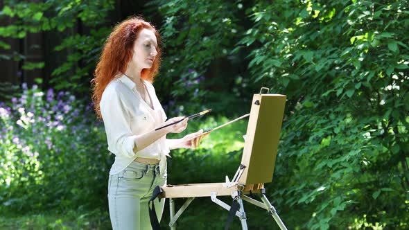 Young Redhead Woman With an Easel in The Forest