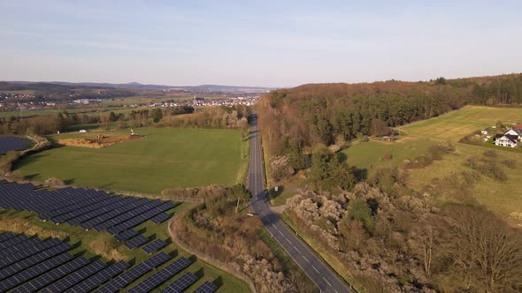European country road leading past a large solar farm in Germany. High aerial fly over shot alt