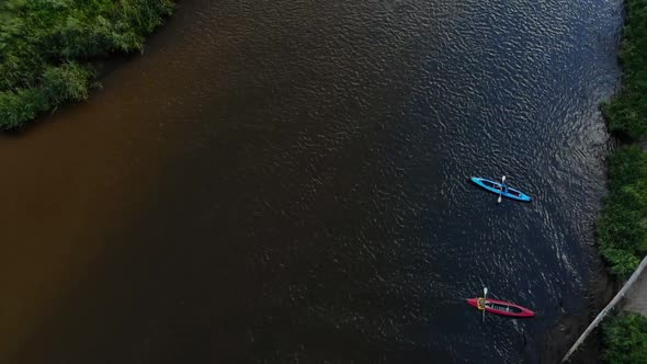 Fly Up Over a Red and a Blue Kayaks with Rowers Drifting Along a Wide River alt