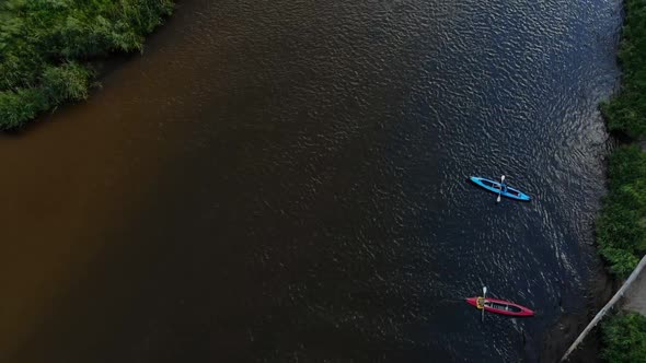 Fly Up Over a Red and a Blue Kayaks with Rowers Drifting Along a Wide River