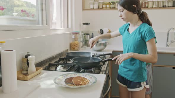 Young kids preparing pancakes in the kitchen using a frying pan alt