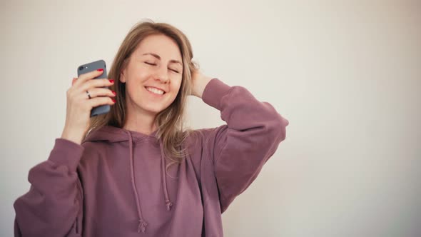 Beautiful Woman Listening To Music on a Smartphone Dancing and Singing Along alt