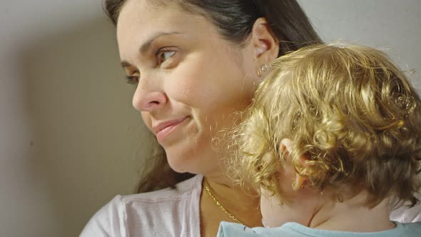 A Mother at Home Holding Her Daughter While Looking Out the Window alt