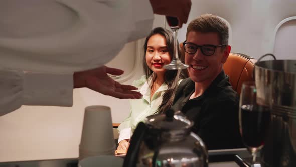 A couple of passengers order champagne from stewardess on airplane, airline service concept