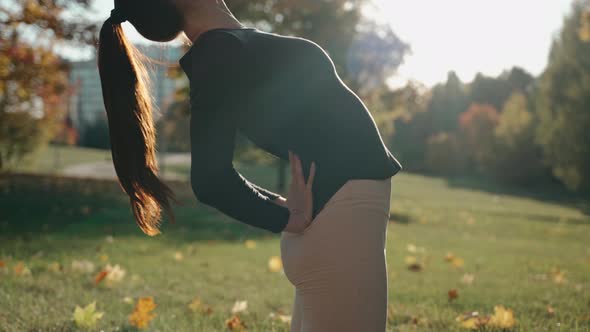 Close Shot of Young Woman Arching Backward in Autumn Park on a Yoga Mat alt