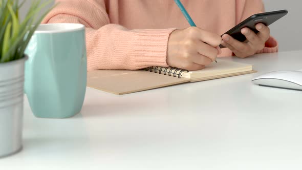 Young Asian women business owners using app smartphones and take notes in the office.