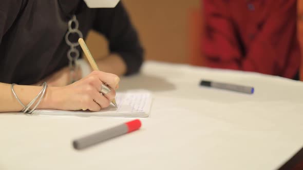 Girl Writes at the Event with a Pencil Marker on a Sheet alt