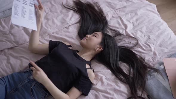 Young Asian Woman Putting Aside Paperwork Taking a Nap in Home Office alt