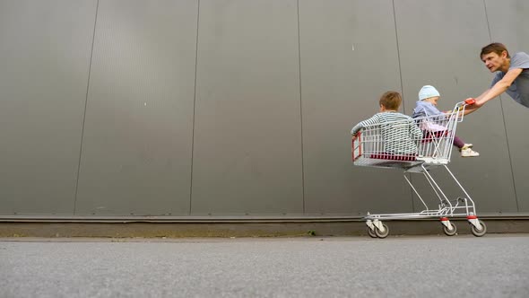 Family with Two Children Going Shopping. Young Consumers in Shopping Cart. Family Having Fun Going