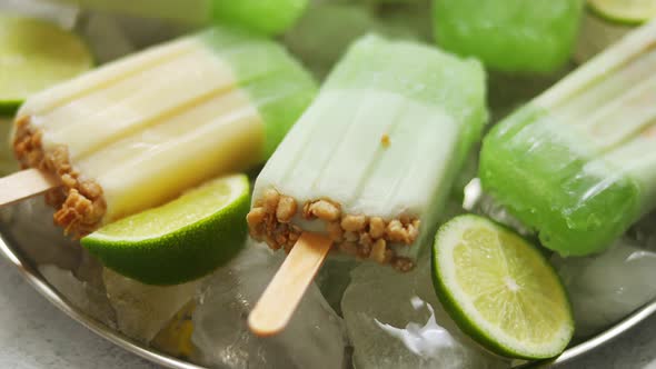 Lime and Cream Homemade Popsicles or Ice Creams Placed with Ice Cubes on Gray Stone Backdrop alt