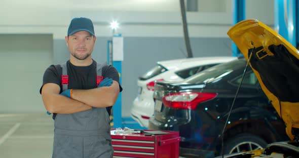 Portrait of a Young Beautiful Car Mechanic in a Car Workshop, in the Background of Service.