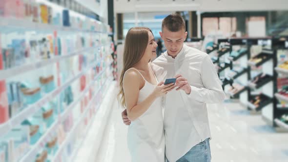 Charming Girl and Nice Guy Are Looking at Reviews on Perfumery Products While alt