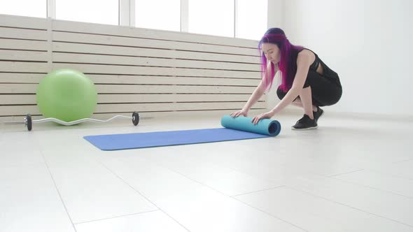 Concept of Sports and Health and Relaxation. Young Woman with a Yoga Mat and Exercises alt