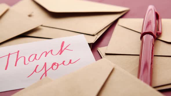 Thank you Message and Envelope on Wooden Table alt