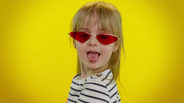 Playful Happy Child Girl in Sunglasses Blinking Eye Looking at Camera with Smile Winking Flirting alt