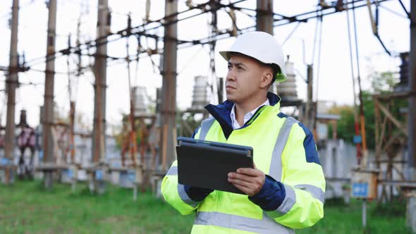 Engineer Man Inspects a Power Line Using Data From Electric Sensors on a Digital Tablet