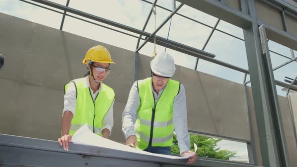 Asian colleague workers people wearing protective safety helmet and work at construction site. alt