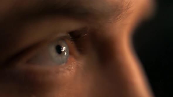 Flashes of light and sparks are reflected in the man's eyes